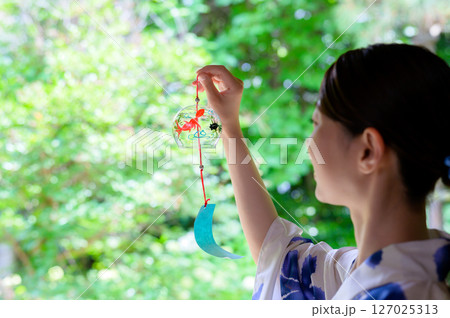 風鈴を手に取る浴衣姿の女性の涼しげな夏のひととき 風鈴を手に取る浴衣姿の女性の涼しげな夏のひととき 127025313