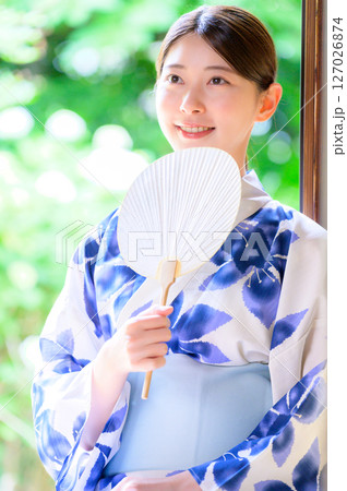 団扇を手に笑顔を見せる浴衣姿の女性の夏の心和む時間 団扇を手に笑顔を見せる浴衣姿の女性の夏の心和む時間 127026874