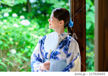 和の空気感あふれる庭を背景に団扇を持つ浴衣姿の女性 和の空気感あふれる庭を背景に団扇を持つ浴衣姿の女性 127026885