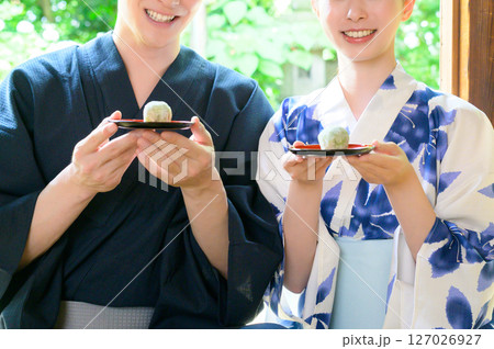 縁側で和菓子を見せ合う浴衣姿の男女が過ごす夏のひととき 127026927
