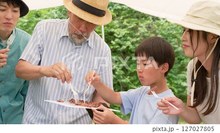 屋外で料理を楽しむキャンプ仲間 127027805