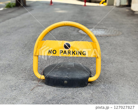 Yellow no parking barrier on asphalt road. Metal sign with warning text placed to block vehicle access in private area. Yellow no parking barrier on asphalt road. Metal sign with warning text placed to block vehicle access in private area. 127027827
