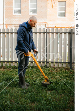 Person Operating Yellow Drill for Garden Maintenance Person Operating Yellow Drill for Garden Maintenance 127028202