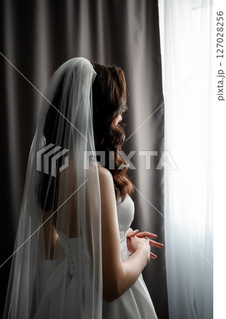 Bride in Veil Gazing Out Window with Anticipation 127028256