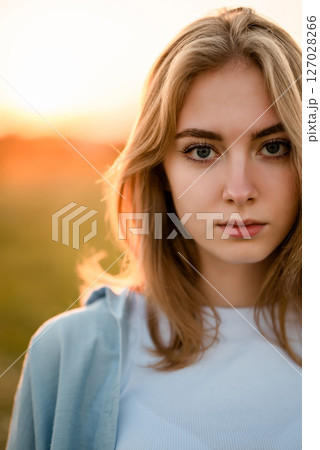 Woman in Field Adjusting Hair at Sunset 127028266
