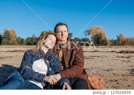 Loving couple walks on beach along sea on sunny autumn day. Weekend and lifestyle concept. High quality photo Loving couple walks on beach along sea on sunny autumn day. Weekend and lifestyle concept. High quality photo 127029859
