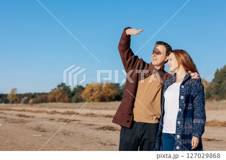 Loving couple walks on beach along sea on sunny autumn day. Weekend and lifestyle concept. High quality photo 127029868
