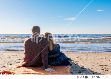 Loving couple walks on beach along sea on sunny autumn day. Weekend and lifestyle concept. Back view. High quality photo 127029880