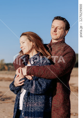 Loving couple walks on beach along sea on sunny autumn day. Weekend and lifestyle concept. Vertical photo. High quality photo 127029900