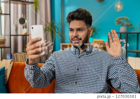 Happy Indian man taking selfie on smartphone communicating video call home online with subscribers Happy Indian man taking selfie on smartphone communicating video call home online with subscribers 127030381