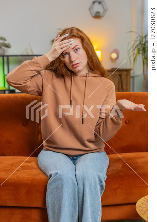 Upset woman making disrespect gesture, disappointed in fail results bad news on sofa couch at home Upset woman making disrespect gesture, disappointed in fail results bad news on sofa couch at home 127030823