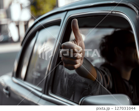 A hand with a thumbs-up gesture is extended out of a car window. Concept of approval and positivity. 127031044