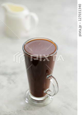 Hot Chocolate in Tall Transparent Glass with Handle on Gray Concrete Background Hot Chocolate in Tall Transparent Glass with Handle on Gray Concrete Background 127031340