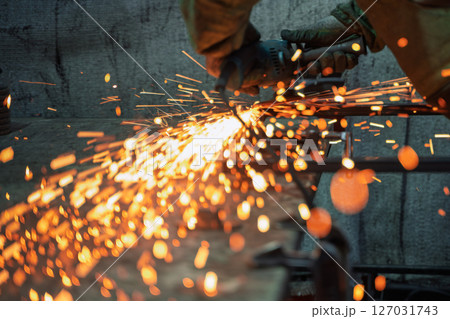 Industrial Metal worker Using Angle Grinder in Workshop with Flying Sparks Industrial Metal worker Using Angle Grinder in Workshop with Flying Sparks 127031743