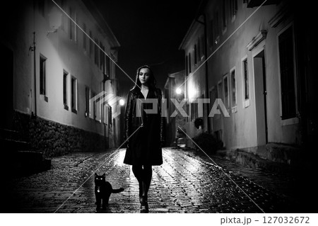 光る石畳を散歩する女性と黒猫 127032672