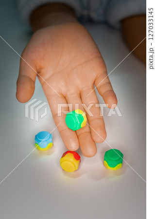 Korean traditional game kit Gonggi. Colourful plastic stones on the hand. 127033145