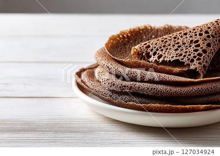 tempting injera in the sunny corner on a white background, in a clean food photography style 127034924