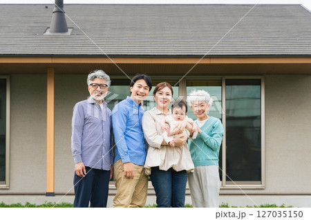 住宅の前に並ぶ三世代家族の集合写真 127035150