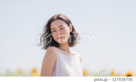 青空とひまわり畑に立つ女性のポートレート　夏の自然風景素材 127036756