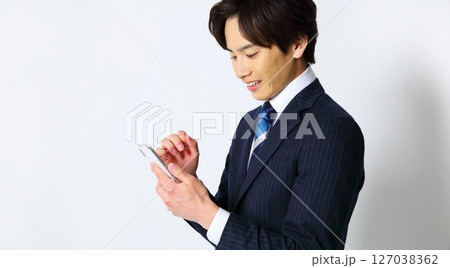 笑顔でスマホを操作する男性会社員イメージ 127038362