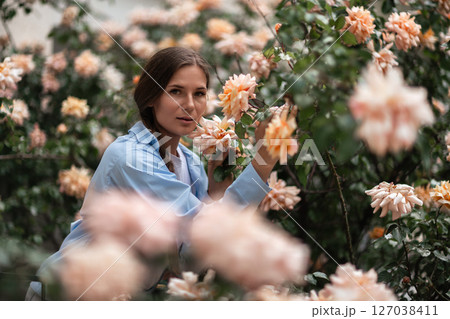 Roses Woman Garden: Woman touches peach roses in garden on summer day, enjoying flowers and nature. Roses Woman Garden: Woman touches peach roses in garden on summer day, enjoying flowers and nature. 127038411