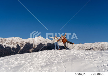 Snow Mountains Winter Fun: Couple celebrating snowy peak achievement, joyful pose, sunny day. 127038686