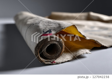 Old rolled paper revealing yellow inside, showcasing vintage texture and historical significance 127042238