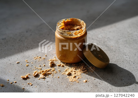 Delicious peanut butter jar with scattered crumbs on a light gray surface 127042240