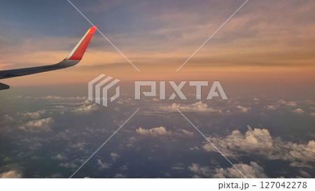 View From Airplane Window of Wing During Sunset. Sky Above Clouds with Vibrant Colors. 127042278