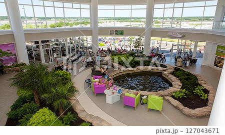 Indoor Oasis: Shoppers Relax by Pond in Bright Atrium with Airpo 127043671