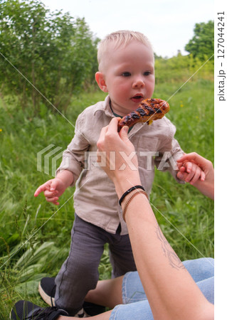 Happy toddler excited about grilled chicken at picnic 127044241