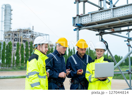 Group of petrochemical workers or technicians work together with one hold laptop and they stand in front the factory and look happiness in workplace. Group of petrochemical workers or technicians work together with one hold laptop and they stand in front the factory and look happiness in workplace. 127044814