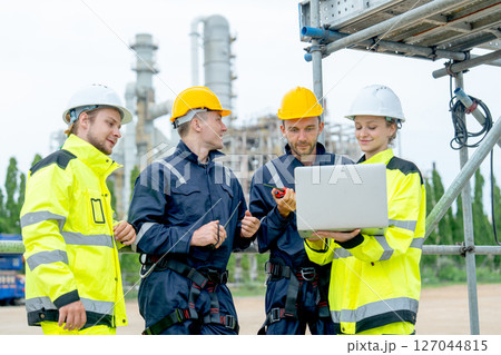 Group of petrochemical workers or technicians work together with one hold laptop and they stand in front the factory. 127044815
