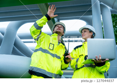 Petrochemical worker man discuss with his coworker hold laptop and they stay in pipeline area in factory workplace. Petrochemical worker man discuss with his coworker hold laptop and they stay in pipeline area in factory workplace. 127044837