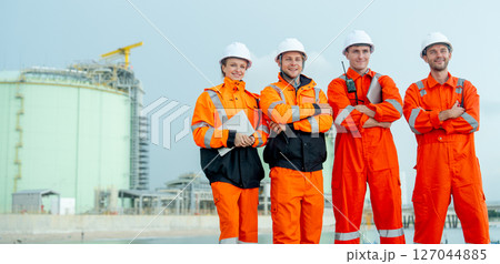 Group of petrochemical or gas factory workers or technicians stand with arm-crossed and stay in front of factory tank near the bay. Group of petrochemical or gas factory workers or technicians stand with arm-crossed and stay in front of factory tank near the bay. 127044885
