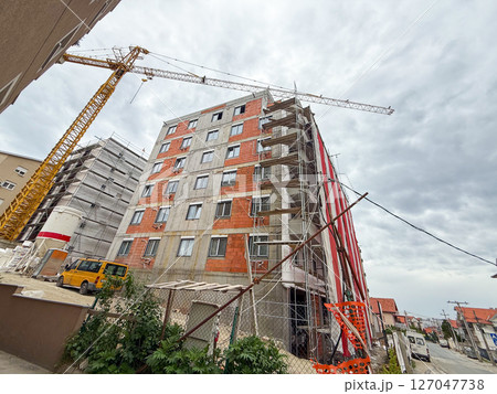 Urban construction site with residential building, scaffolding, and crane. Modern development area with equipment and infrastructure installation Urban construction site with residential building, scaffolding, and crane. Modern development area with equipment and infrastructure installation 127047738