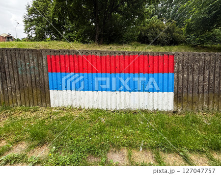 Painted Serbian flag on concrete wall in a public park. Patriotic urban art expressing national identity in everyday surroundings. 127047757