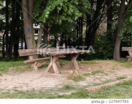 Old wooden picnic bench in a shaded forest clearing. A quiet corner in nature for rest and conversation. Old wooden picnic bench in a shaded forest clearing. A quiet corner in nature for rest and conversation. 127047763