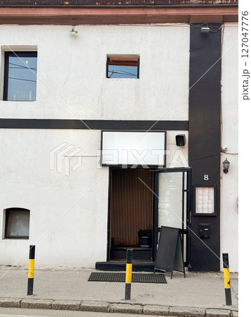 Minimalist restaurant entrance with blank signboard and black-and-white facade. Modern urban design in European street setting Minimalist restaurant entrance with blank signboard and black-and-white facade. Modern urban design in European street setting 127047776