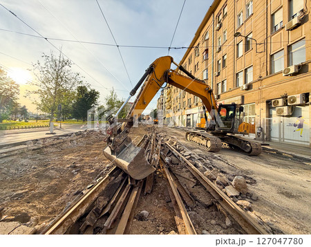 Excavator working on tram track dismantling. City infrastructure under construction. Excavator working on tram track dismantling. City infrastructure under construction. 127047780