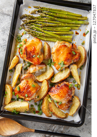 Sheet Pan Honey Mustard Chicken thighs With Potatoes And Asparagus close-up on a table. vertical top view 127047837