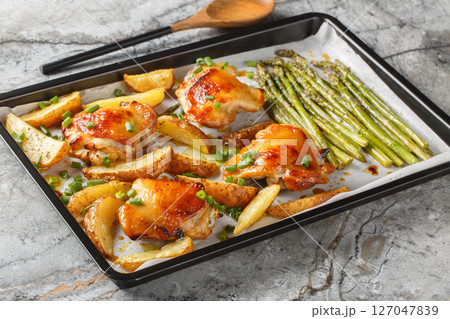 roasted chicken with potatoes and green asparagus close-up of a baking sheet. horizontal 127047839