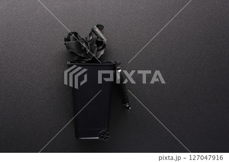 Trash can with garbage on a black background. Trash can black and black garbage. Trash can with lid on a black background. Black on black. Trash can with garbage on a black background. Trash can black and black garbage. Trash can with lid on a black background. Black on black. 127047916
