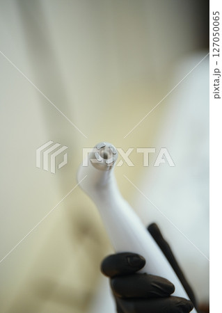 Portable dental cleaning tool held by gloved hand in clinic setting Portable dental cleaning tool held by gloved hand in clinic setting 127050065