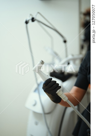 Hand holding a device for skin treatment in a clinical environment Hand holding a device for skin treatment in a clinical environment 127050077