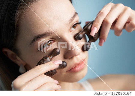 Woman using a facial massage tool for relaxation and skincare at home Woman using a facial massage tool for relaxation and skincare at home 127050164