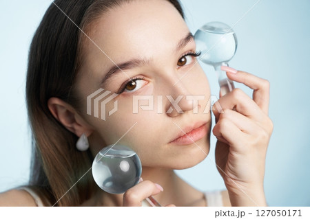 Woman using facial massage tools for skincare routine in bright setting Woman using facial massage tools for skincare routine in bright setting 127050171