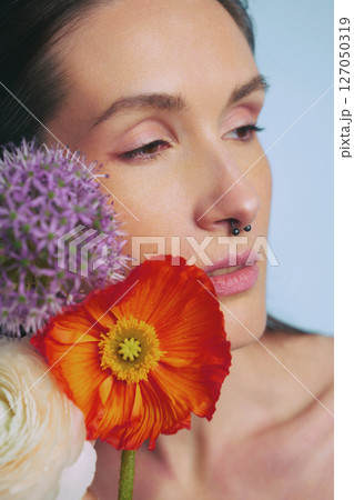 Beautiful woman with vibrant flowers on her shoulder during a serene moment Beautiful woman with vibrant flowers on her shoulder during a serene moment 127050319