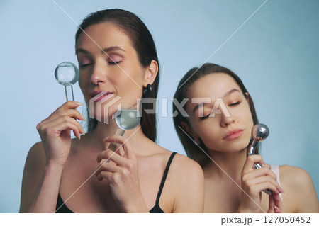 Women enjoying skincare routine with facial tools in tranquil setting 127050452
