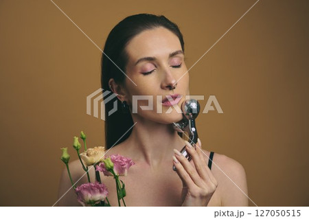 Facial treatment with a beauty tool and flowers against a warm backdrop 127050515